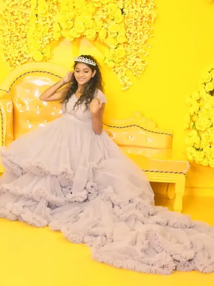 A duplicate of a striking maternity photo with a woman in a light purple gown seated on a yellow vintage-style couch against a matching yellow floral background.