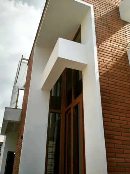 The same facade after completion. Baliapattnam bricks have been cladded onto the structure, and the fenestration is complete, transforming the building's appearance.