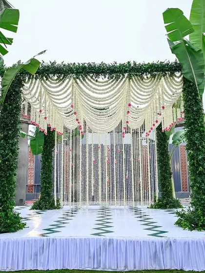 A frontal view of the eco-friendly mandap, highlighting the symmetry of the banana plant pillars and the beautiful draping of the jasmine flower canopy.