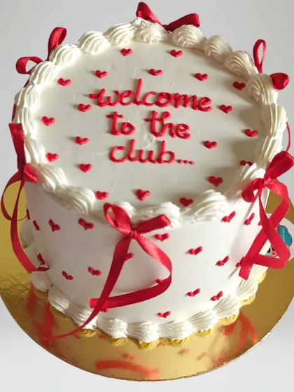 A fun "Welcome to the club" cake with red ribbons and hearts. This design is perfect for celebrating a new job, marriage, or any new life chapter.