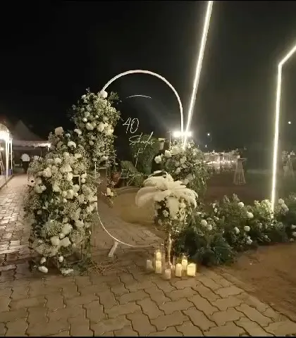 The entrance to the '40 Shades of Elegance' party, featuring a floral-adorned circular arch and modern light bars to welcome guests.