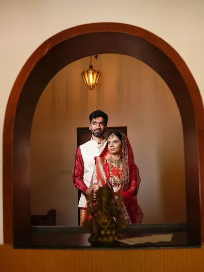 A creatively framed shot of the couple through an archway, adding depth and an artistic touch to their wedding portrait.