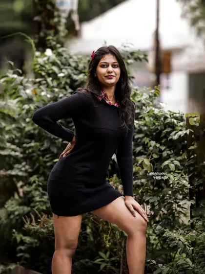 A powerful stance against a green, leafy background, showcasing the simple but effective elegance of a little black dress.