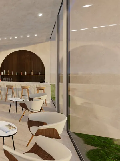 The waiting area is defined by large glass walls that blur the line between inside and out. The design uses arches and soft, curved furniture to create a tranquil space for guests before their session.