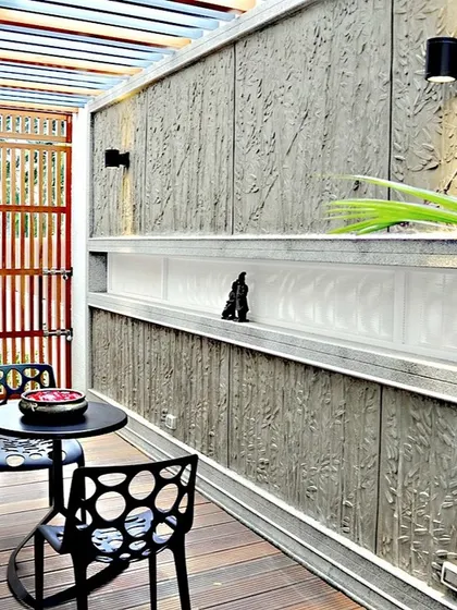 This semi-outdoor patio features a textured concrete wall and a built-in niche. The design provides a private, sheltered space for seating while maintaining a connection to the outdoors.
