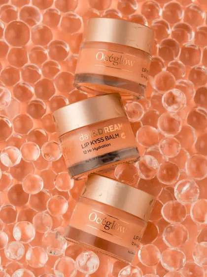 A playful and eye-catching flatlay of Océeglow lip balms stacked on a bed of translucent orange hydrogel beads. The repetition of shapes and the monochromatic color scheme create a visually satisfying and modern composition that highlights the product's packaging.