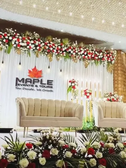 A grand and traditional stage design featuring a rich combination of red and white flowers with golden leaf accents. The three-part seating arrangement provides ample space for family on the big day.