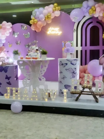 We designed this whimsical butterfly theme for Jhaanvi's first birthday. The decor features a lovely purple and peach color scheme, butterfly-printed pedestals, and a beautiful balloon arch with gold accents.
