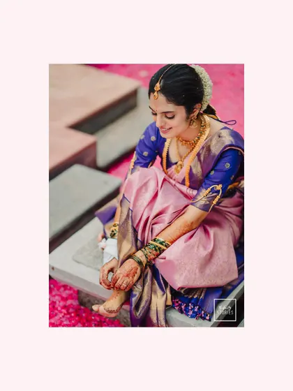 A candid moment of the bride adjusting her toe ring while seated on a bed of petals. It's a quiet, personal moment captured beautifully.