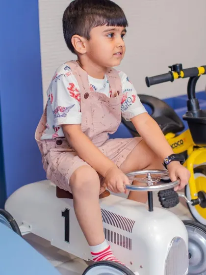 A young boy enjoying a ride on one of our classic toy cars. We have a variety of vehicles for little drivers to choose from.