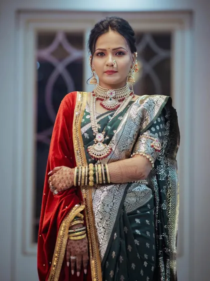 A stunning solo portrait of the bride in her royal wedding attire. The combination of a green paithani saree and a red velvet shawl creates a regal and unique look.