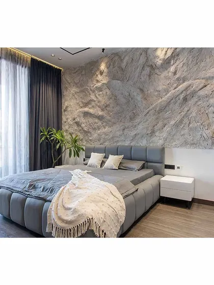 A full view of the bed and the dramatic rock wall, showcasing the contrast between the rough stone and the soft, comfortable bedding.