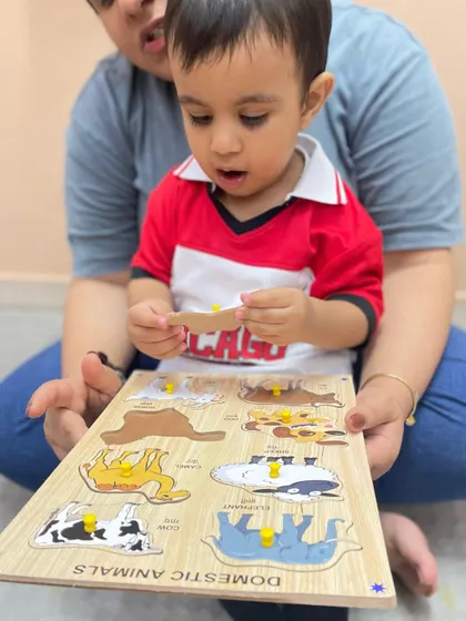 A mother holds a domestic animal puzzle as her child examines a piece. Puzzles are fantastic tools for teaching vocabulary, matching, and problem-solving.