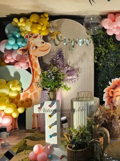 The friendly giraffe prop is a highlight of the pastel jungle theme, surrounded by yellow and mint green balloons.
