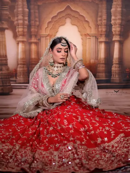 A graceful seated pose where the bride is adjusting her maang tikka. This candid-style shot adds a touch of softness and romance to the bridal series.