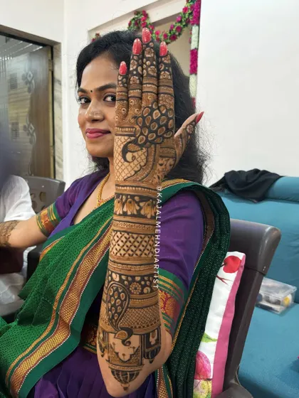 A happy client showing off her peacock-themed bridal henna. The design flows beautifully from her palms to her arms.