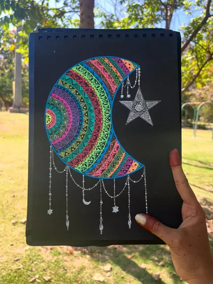 The colorful moon mandala held up against a natural background, showing how it looks in different lighting.