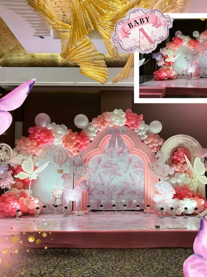 A detailed look at the pink stage backdrop, featuring a Dior-inspired print, butterfly accents, and a beautiful balloon arch in shades of pink, white, and coral.