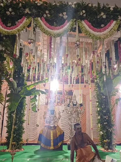 A traditional ceremony in progress, with the priest and deities inside a beautifully decorated mandap.