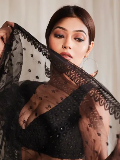 A creative shot using the sheer dupatta to frame the model's face. This adds a layer of mystery and artistry to the portrait.