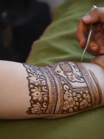 A close-up of my hand at work, carefully drawing a design on a client's arm. Every line is drawn with precision and care.