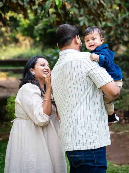 A candid, over-the-shoulder shot of a baby boy smiling at his mom. These unposed, natural moments during an outdoor family shoot are often the most cherished.