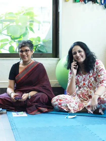 A moment of connection and a smile, as one woman takes a call while another listens to the group.