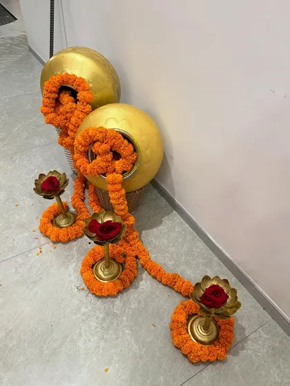 Traditional Diwali decor elements, including brass pots with overflowing marigold garlands and lotus-shaped diyas.