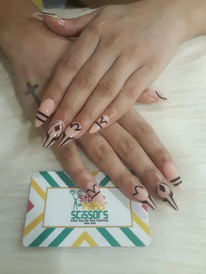 A very graphic and edgy design with sharp, abstract black line work on a nude base. This custom art on stiletto extensions is for someone who wants a truly unique look.