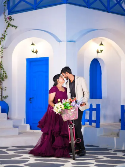 A sweet kiss shared over a bicycle full of flowers. The Santorini-style backdrop makes this pre-wedding photo feel like a destination shoot.