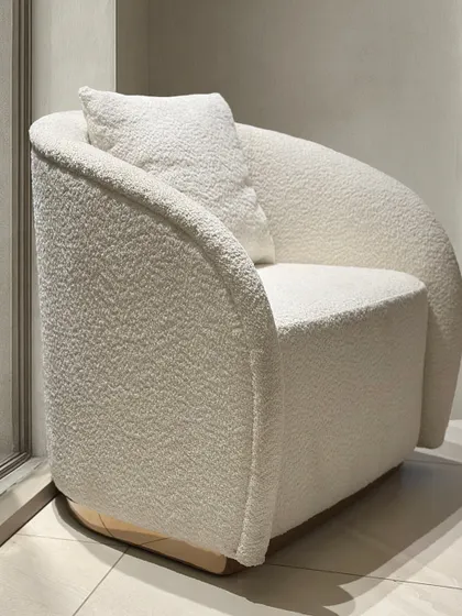 This angle showcases the continuous curve of the armchair's back and arms. The seamless design, combined with the solid, upholstered base, gives the piece a grounded yet elegant presence suitable for modern interiors.