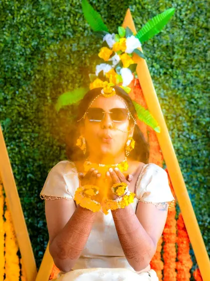 A fun and playful shot of the bride blowing turmeric during her Haldi ceremony.