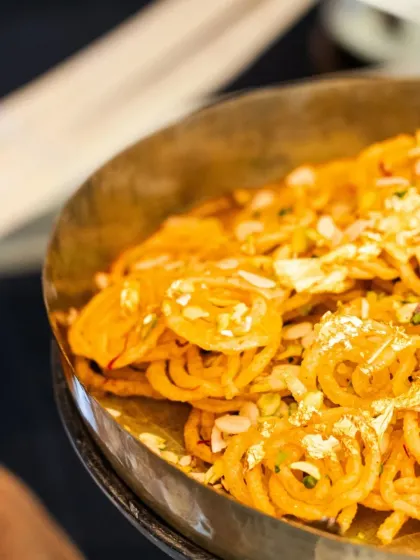 A touch of luxury for a wedding celebration. This platter of glistening jalebis, garnished with delicate edible gold leaf, adds a traditional yet opulent feel to the dessert spread.