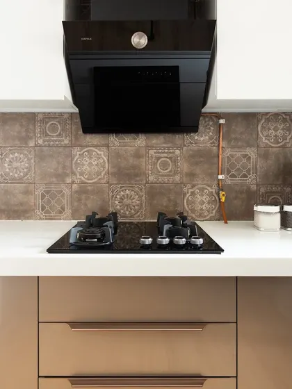 The kitchen in the Mumbai home, with a stylish patterned backsplash and modern beige cabinets.