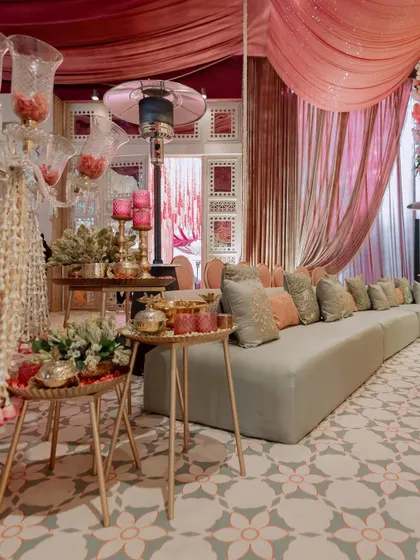 We create comfortable and stylish lounge areas for guests. This one features long sofas with a mix of pastel cushions, set against a backdrop of draped fabric and patterned flooring.