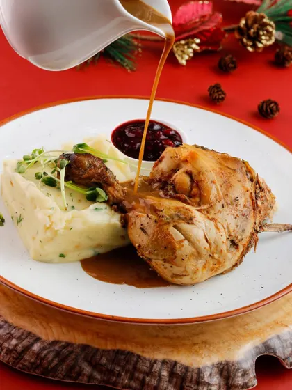 A classic Christmas dish of roasted chicken leg with mashed potatoes and cranberry sauce.