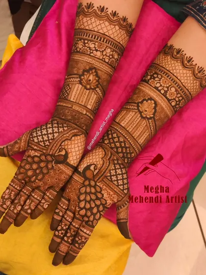 This design prominently features graceful peacocks on the palms, with their feathers forming a beautiful, flowing pattern. The arms are decorated with bands of lotus and jharokha motifs.