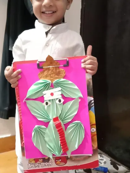 The smile on this child's face shows the pride he feels in his creation. Celebrating and displaying each child's artwork is essential for building their confidence.