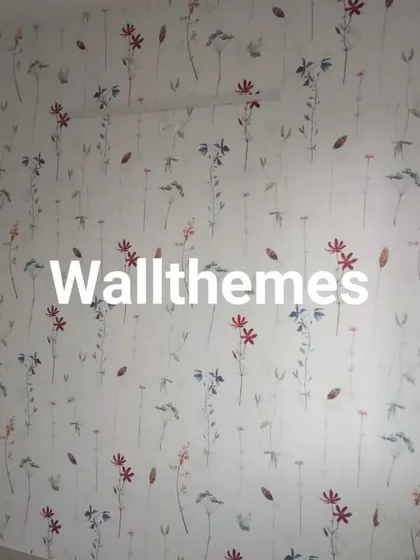A full wall covered in a whimsical, scattered floral print wallpaper, perfect for a bedroom or study area.