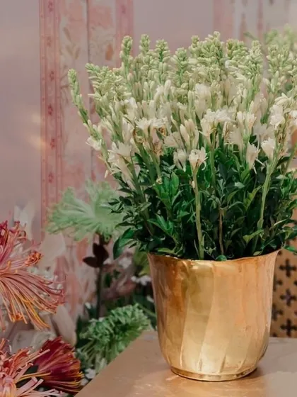 A beautiful detail shot of fresh tuberoses in a hammered brass pot, set against a backdrop of custom-printed fabric.