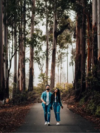 A full-length shot of a couple walking down a road in a beautiful forest, a classic and romantic pre-wedding scene.