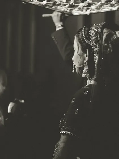 An artistic black and white shot of the bride's entry under a 'phoolon ki chadar', a traditional and beautiful moment.