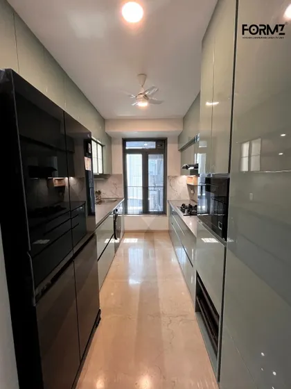 A wide-angle view of a parallel kitchen, showing the relationship between the cooking and storage zones. The glossy finish on the cabinets and floor reflects light, making the space feel open and airy.