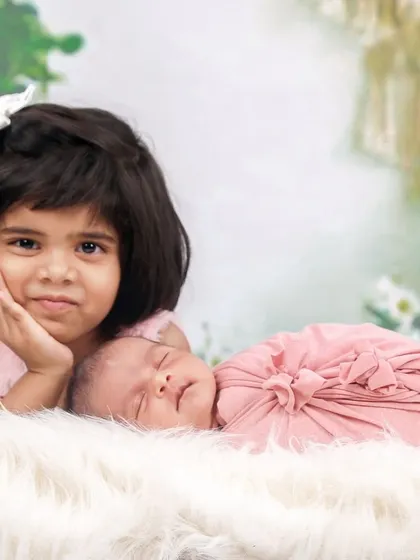 A slightly different angle of this sweet sibling moment, capturing the older sister's curious and loving expression.