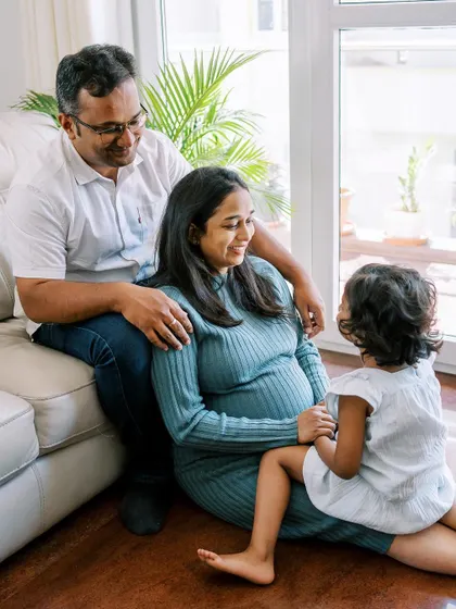A family shares a moment of connection during their maternity shoot. The older sister is full of curiosity about the new baby on the way.