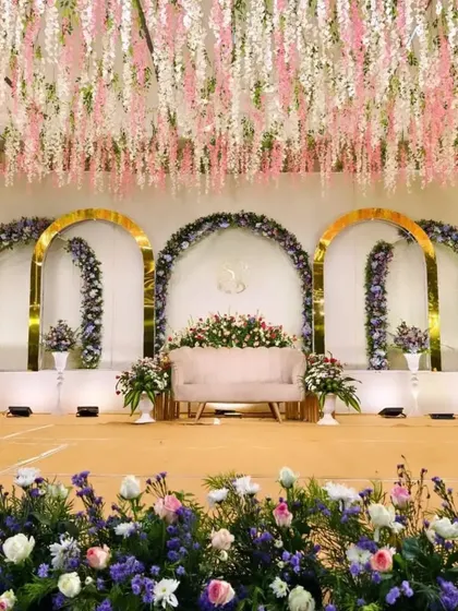 This premium reception decor shows how we can transform a large hall. The combination of a hanging floral ceiling, golden arches, and lush flower arrangements creates an atmosphere of pure elegance and celebration.