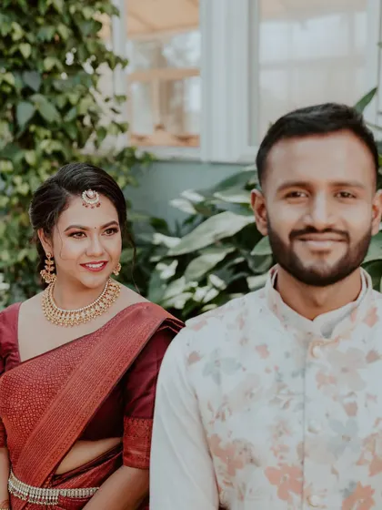 An intimate engagement portrait. The bride-to-be wears a beautiful maroon silk saree, and her makeup is soft and natural, with a simple bindi and traditional gold jewellery for an understated, elegant look.