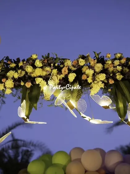 A close-up of the floral arrangement on the entrance arch, with delicate, illuminated butterflies that seem to flutter among the flowers. These small lighting details make a big impact.
