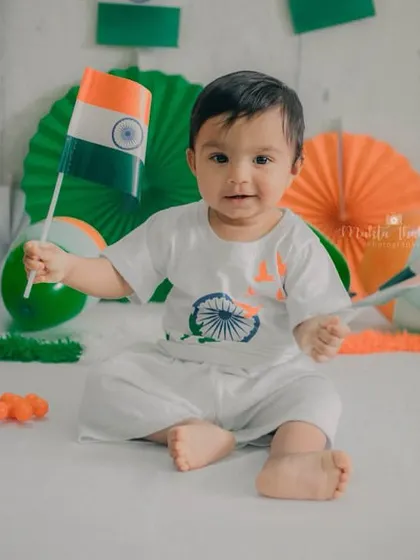 Waving two flags with a proud and happy look. This image is full of patriotic spirit and captures the fun of a themed baby photoshoot.