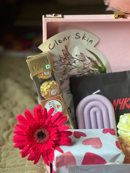 A close-up on the contents of the 'Thank You' hamper, highlighting the Ferrero Rocher chocolates, a designer candle, and a face mask.